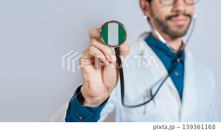 Doctor holding stethoscope with Nigeria flag. Nigeria health and care concept, Nigeria flag on stethoscope 139361168