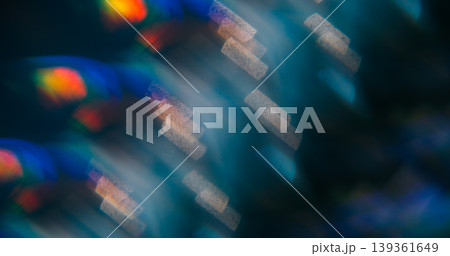 Night bokeh prism. Reflection glow. Color striped light on defocused black background. Vibrant abstract blue violet orange twinkle luminosity. Night bokeh prism. Reflection glow. Color striped light on defocused black background. Vibrant abstract blue violet orange twinkle luminosity. 139361649