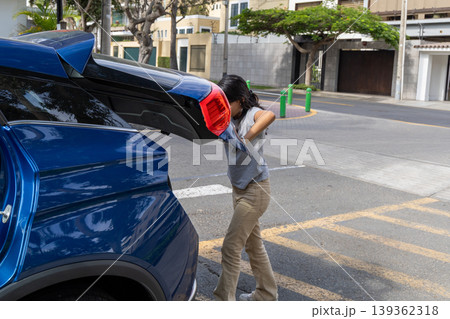 A teenager is pulling a blue car out of a parking lot 139362318