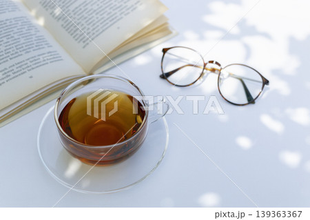 白いテーブルで楽しむ紅茶と開いた本と眼鏡のある穏やかな読書時間(コピースペースあり) 白いテーブルで楽しむ紅茶と開いた本と眼鏡のある穏やかな読書時間(コピースペースあり) 139363367