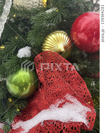 Christmas decorations with colorful ornaments and a red ribbon on a snowy tree background Christmas decorations with colorful ornaments and a red ribbon on a snowy tree background 139364281