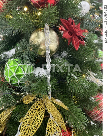 Christmas tree with festive ornaments and decorations including gold dragonfly, red flower, and greenery Christmas tree with festive ornaments and decorations including gold dragonfly, red flower, and greenery 139364282