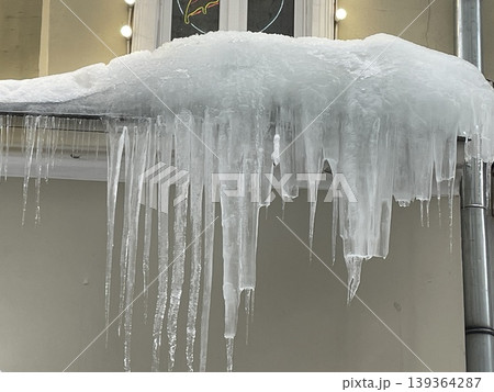 Icicles hanging from roof edge during winter season as frozen water forms unique shapes 139364287