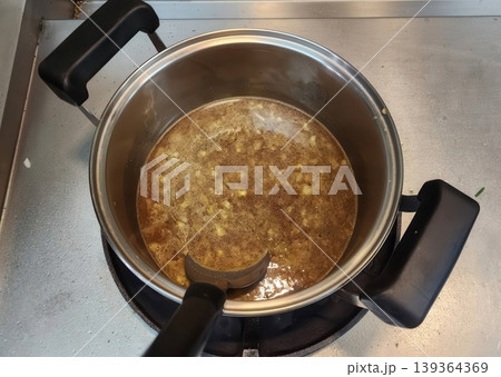 Savory Homemade Soup Simmering in a Stainless Steel Pot on a Kitchen Stove Savory Homemade Soup Simmering in a Stainless Steel Pot on a Kitchen Stove 139364369