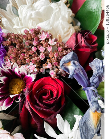Beautiful flower bouquet of many colors and textures. Floral arrangement with deep red roses, white daisies, delicate pink blooms and purple irises among lush green leaves. Perfect for celebration Beautiful flower bouquet of many colors and textures. Floral arrangement with deep red roses, white daisies, delicate pink blooms and purple irises among lush green leaves. Perfect for celebration 139364456