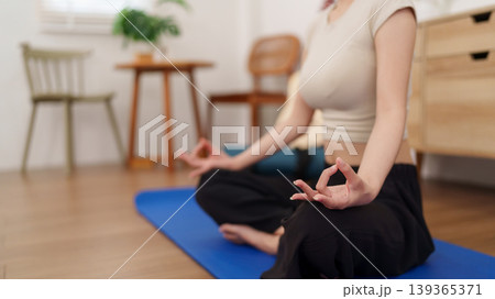 Asian women practice yoga meditation sitting lotus position on blue mat relax mindfulness wellness exercise routine healthy lifestyle workout training at home Asian women practice yoga meditation sitting lotus position on blue mat relax mindfulness wellness exercise routine healthy lifestyle workout training at home 139365371