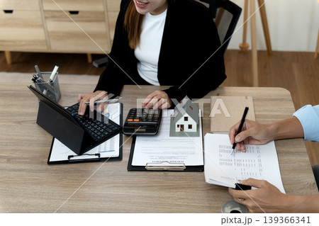 Asian business professionals discuss real estate financial planning using tablet calculator at office meeting for property investment mortgage calculation home purchase advice data analysis Asian business professionals discuss real estate financial planning using tablet calculator at office meeting for property investment mortgage calculation home purchase advice data analysis 139366341