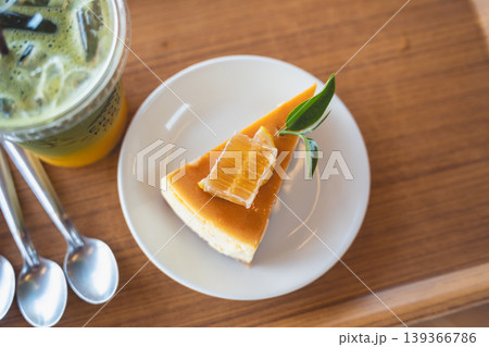 Delicious slice of caramel cheesecake garnished with honeycomb and leaf, served on a white plate beside an iced drink on a wooden table Delicious slice of caramel cheesecake garnished with honeycomb and leaf, served on a white plate beside an iced drink on a wooden table 139366786