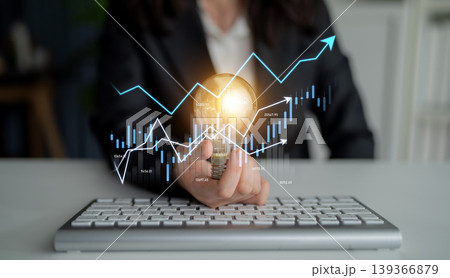 Business professional analyzing financial data using digital graphs and charts while holding a light bulb to symbolize innovative ideas and solutions Scalp Business professional analyzing financial data using digital graphs and charts while holding a light bulb to symbolize innovative ideas and solutions Scalp 139366879