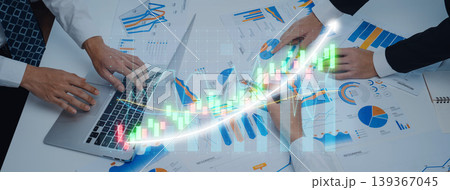 Business team collaborating on financial report analysis with laptop and charts displaying growth trends in graph format during meeting session Axiom Business team collaborating on financial report analysis with laptop and charts displaying growth trends in graph format during meeting session Axiom 139367045