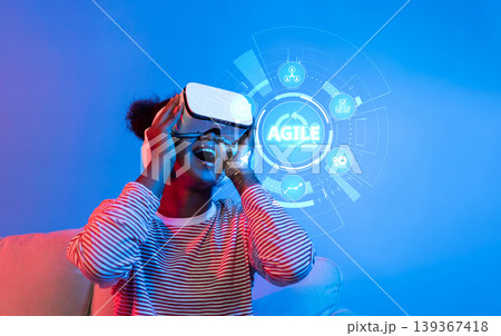 Young person experiencing virtual reality technology with an emphasis on agility and innovation in a modern, colorful environment. XDMCP Young person experiencing virtual reality technology with an emphasis on agility and innovation in a modern, colorful environment. XDMCP 139367418