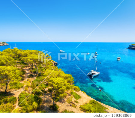 Aerial view of luxury yachts and boats anchored in a turquoise bay on the coast of Mallorca, Spain. Aerial view of luxury yachts and boats anchored in a turquoise bay on the coast of Mallorca, Spain. 139368869