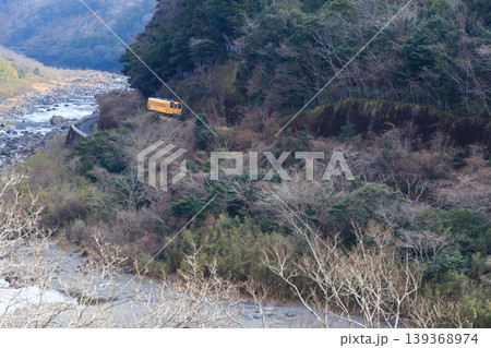 四万十川の渓谷に沿って予土線の黄色い気動車が崖に張り付いて走っていく 四万十川の渓谷に沿って予土線の黄色い気動車が崖に張り付いて走っていく 139368974