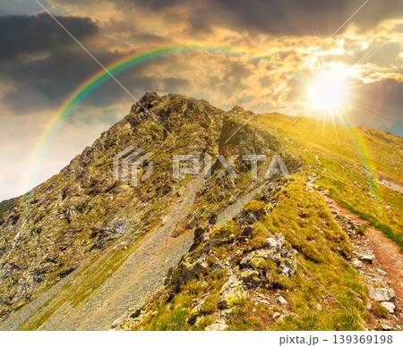 sunset over mountain scenery in summer. gorgeous mountainous landscape. background with rocky cliffs and grassy hillsides under a cloudy sky. ridge of southern mountains under rainbow 139369198
