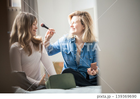 Mother applying makeup to young woman bonding indoors Mother applying makeup to young woman bonding indoors 139369690