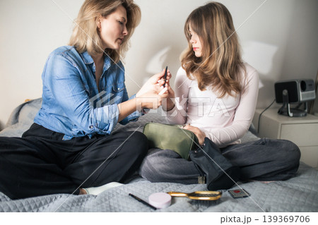 Mother teaching daughter makeup routine at home 139369706