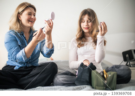 Mother and daughter applying makeup bonding together Mother and daughter applying makeup bonding together 139369708