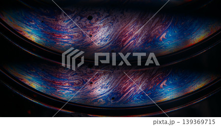 Oil fluid. Gasoline leak. Defocused blue yellow purple color round bubble liquid paint blend wave floating on abstract dark black background Oil fluid. Gasoline leak. Defocused blue yellow purple color round bubble liquid paint blend wave floating on abstract dark black background 139369715