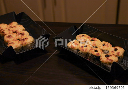 Warm Japanese baked sushi rolls in sleek black takeout boxes on a dark background Warm Japanese baked sushi rolls in sleek black takeout boxes on a dark background 139369793