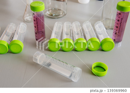 laboratory test tubes with green caps and sample liquids on table 139369960