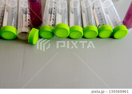 laboratory test tubes with green caps and sample liquids on table 139369961