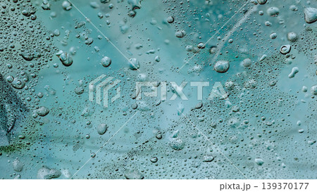 Teal water texture of droplets, bubbles, condensation, and liquid patterns on glass. Natural blurred background texture for wellness, skincare, poster, banner, wallpaper, mockup, copy space Teal water texture of droplets, bubbles, condensation, and liquid patterns on glass. Natural blurred background texture for wellness, skincare, poster, banner, wallpaper, mockup, copy space 139370177