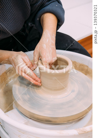Hands craft clay. Pottery workplace. Unrecognizable experienced woman artisan shaping raw using wheel in professional ceramic studio. 139370321