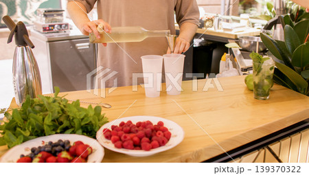 Alcohol pouring. Drink making. Unrecognizable barman hands preparing classic beverage using measuring tool into glass with crushed ice lime at workplace. Alcohol pouring. Drink making. Unrecognizable barman hands preparing classic beverage using measuring tool into glass with crushed ice lime at workplace. 139370322