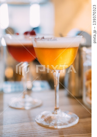 Frothy cocktail. Aperitif glass. Mixed drink served on metal tray. Bar liquid with whipped white top dried flower petals aromatic garnish. Frothy cocktail. Aperitif glass. Mixed drink served on metal tray. Bar liquid with whipped white top dried flower petals aromatic garnish. 139370323