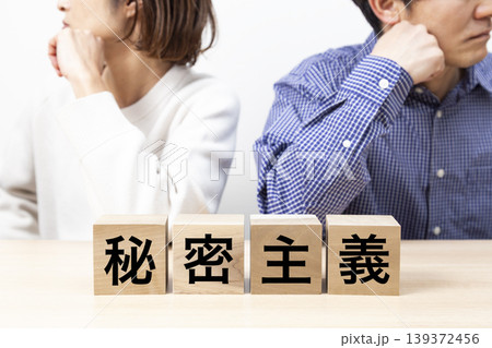 「秘密主義」と書かれたブロックと喧嘩をする夫婦 「秘密主義」と書かれたブロックと喧嘩をする夫婦 139372456
