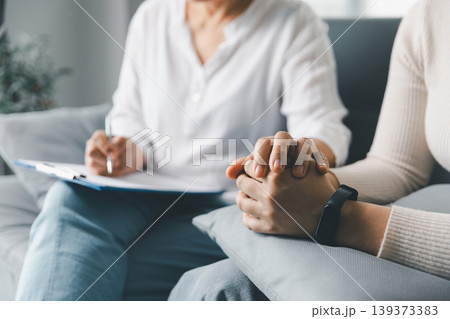Mental health support concept with therapist touching anxious woman's hands during counseling session at home, showing empathy, trust, reassurance, emotional care, healing and human connection. Mental health support concept with therapist touching anxious woman's hands during counseling session at home, showing empathy, trust, reassurance, emotional care, healing and human connection. 139373383