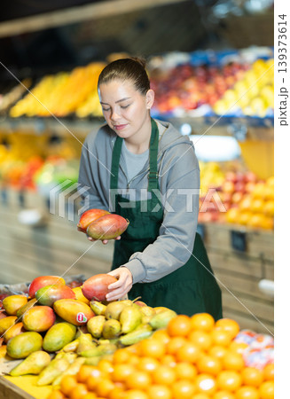 seller lays out a ripe mango on the counter of a fruit shop seller lays out a ripe mango on the counter of a fruit shop 139373614