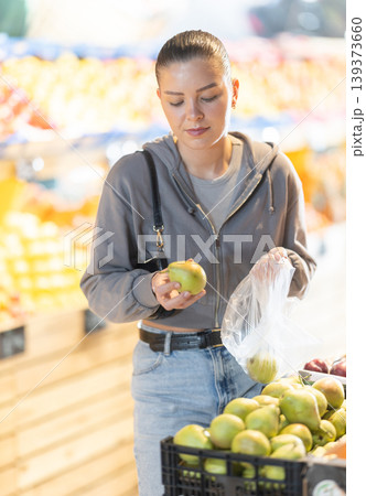 Young woman buyer choosing pears at vegetable market Young woman buyer choosing pears at vegetable market 139373660