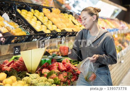 Young woman chooses peppers in store 139373778