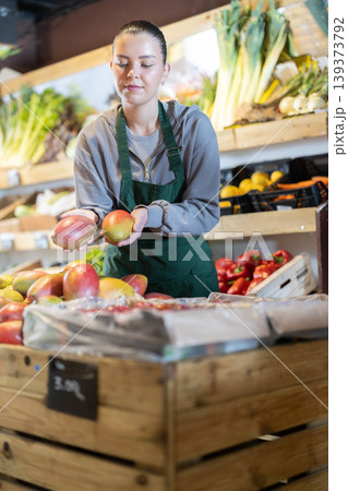 While working in supermarket, employee forms display case, puts ripe mango in pile While working in supermarket, employee forms display case, puts ripe mango in pile 139373792