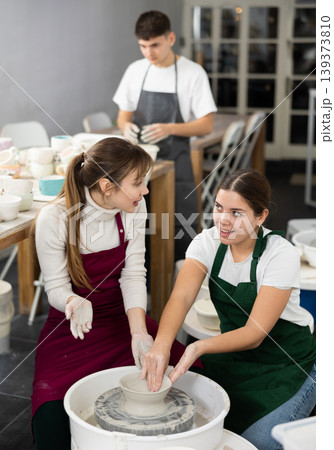 Woman working with pottery wheel and master giving instructions Woman working with pottery wheel and master giving instructions 139373810