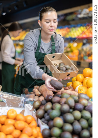 While working in shop, employee forms display case, puts avocado in pile While working in shop, employee forms display case, puts avocado in pile 139373815
