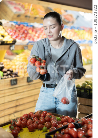 Young woman buyer choosing tomatoes at vegetable market Young woman buyer choosing tomatoes at vegetable market 139373822