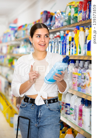 in store, girl carefully chooses household chemicals 139373859