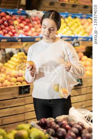 Young woman chooses lemons in vegetable shop Young woman chooses lemons in vegetable shop 139374010