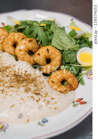 Healthy appetizer. Tasty salad. Delicious meal with grilled crunchy prawn row on greens garnish quail egg plated with whipped sauce. Healthy appetizer. Tasty salad. Delicious meal with grilled crunchy prawn row on greens garnish quail egg plated with whipped sauce. 139374053