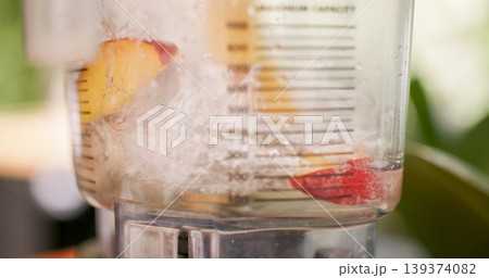 Pouring water blender. Fruit drink preparing. Fresh peaches pieces in automatic machine covering with alcohol syrup liquid in professional bar. 139374082