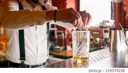 Fresh cocktail. Alcohol beverage. Unrecognizable professional male barman hands serving decorating drink on bar counter. 139374298