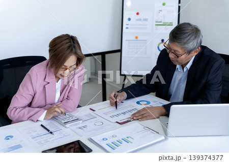 Asian adult business professionals calculating financial data analyzing market reports collaborating corporate office setting for strategic planning development 139374377