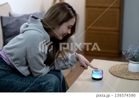 Asian young adult woman activating smart lamp home living room modern interior enjoying colorful ambient lighting digital technology user experience smart living home automation Asian young adult woman activating smart lamp home living room modern interior enjoying colorful ambient lighting digital technology user experience smart living home automation 139374390