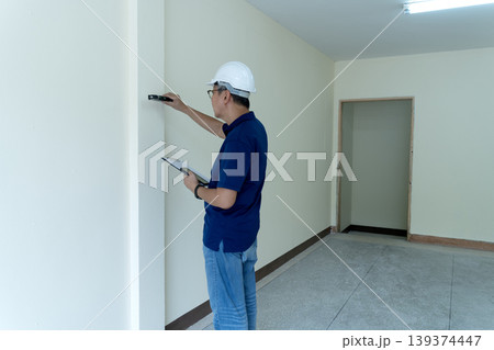 Adult Asian Construction Engineer Inspecting Wall Alignment Using Level Tool Documenting Quality Control New Building Project Site 139374447