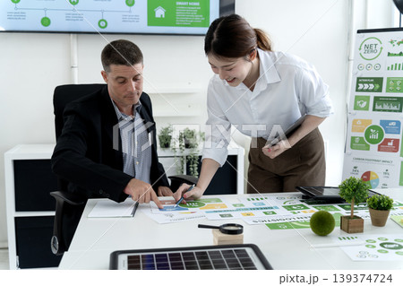 Business professionals discuss green strategy sustainability goals net zero initiatives modern office collaboration analyzing environmental impact data Business professionals discuss green strategy sustainability goals net zero initiatives modern office collaboration analyzing environmental impact data 139374724