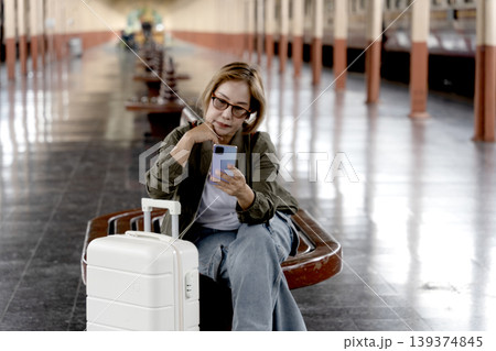 Asian woman traveler adult passenger using smartphone train station platform waiting for departure journey communication Asian woman traveler adult passenger using smartphone train station platform waiting for departure journey communication 139374845