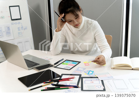 Asian young adult woman designing user interface experience for mobile app development creative professional working office Asian young adult woman designing user interface experience for mobile app development creative professional working office 139375070