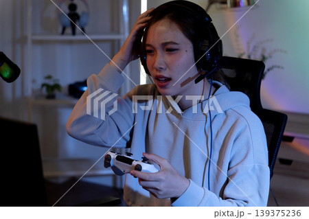 Asian adult woman streaming gaming podcast content creation using tablet microphone headphones with joy at home studio personal room 139375236